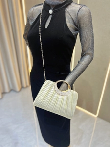 Detailed view of golden evening clutch featuring pleated texture and rhinestone ring handle