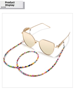 Close-up of golden sunglasses with a feather charm and colorful beaded anti-lost chain