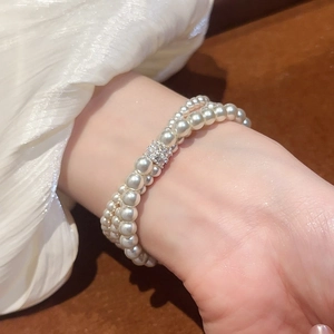 Detail view of a double-layer pearl bracelet with zircon clasp on woman's wrist