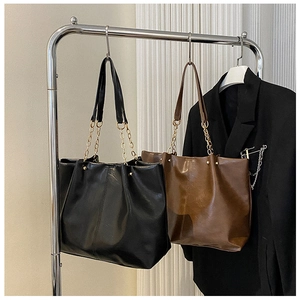 Vue détaillée de grands sacs cabas en similicuir noir et marron avec chaînes en métal