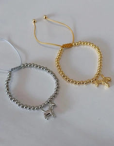 Detail of adjustable woven bracelets with gold and silver balloon dog charms