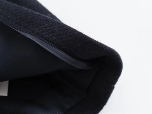 Macro detail of black wool coat showing double stitching, grosgrain trim, and twill lining