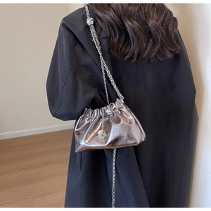 Close-up of silver pleated cloud bag with metallic chain and pearl charm detail