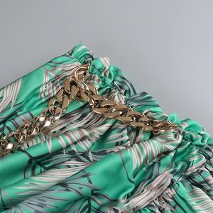 Detail of tropical palm print fabric with textured gold chain strap and gathered waist