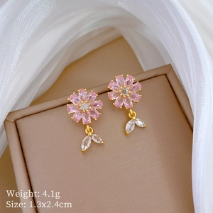 Detail of flower earring with pink zircon petals and golden base on a jewelry box