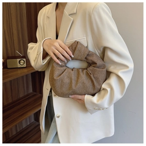 Detail of a brown textured fabric dumpling bag with a unique knot handle design