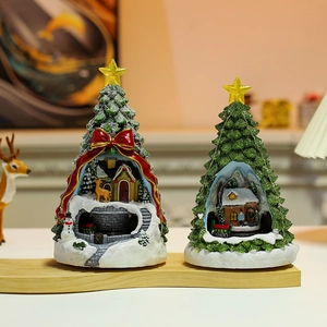 Close-up of glowing Christmas tree ornaments with miniature snow house scenery