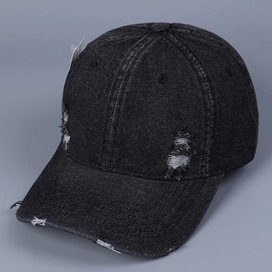 Detail of distressed black denim baseball cap with vintage frayed edges and side tags