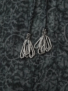 Detailed close-up of dark grey metallic print fabric with intricate beaded fringe tassels