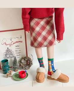 Close-up of girls Christmas outfit with red knit sweater, plaid skirt and festive socks