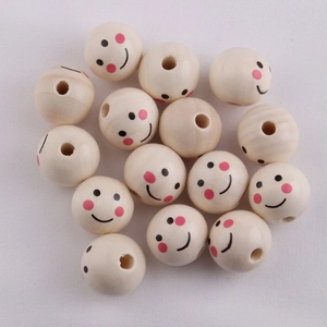 Macro shot of 20mm natural wood beads with smiley face patterns on a white cloth background