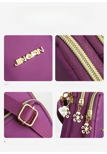 Detail view of purple nylon bag featuring golden hardware and floral zipper pulls