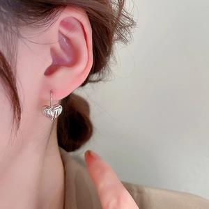 Close-up of a silver crumpled heart earring with minimalist metallic finish on model