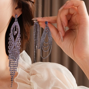 Close-up of long purple crystal tassel earrings worn with an elegant white organza top