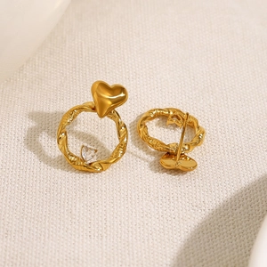 Elegant gold heart twist hoop earrings with sparkling cubic zirconia on fabric background