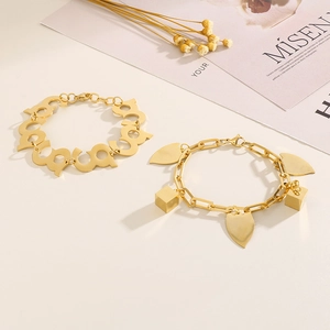 Close-up of gold geometric charm bracelet with cube pendants on a stylish background