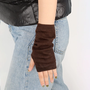 Detail of dark brown knitted fingerless gloves showing ribbed texture and slouchy arm fit