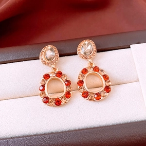 Macro di orecchini vintage con cristalli rossi e champagne su sfondo di pelle marrone