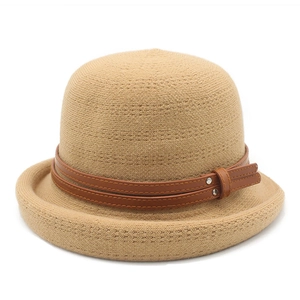 Detail of camel knit bucket hat featuring brown leather strap and silver metal buckle