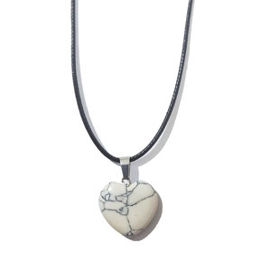 Macro detail of white turquoise heart pendant with black texture on black wax cord