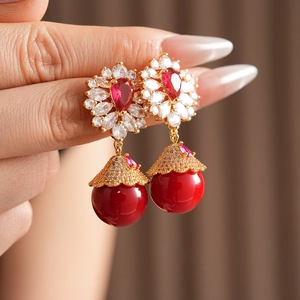 Gros plan de boucles d'oreilles vintage fleurs et gouttes rouges sur une main