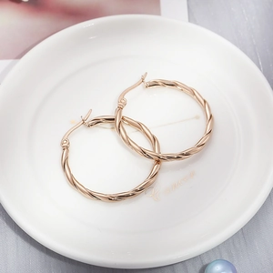 Detailed view of rose gold twisted hoop earrings placed inside a white ceramic dish