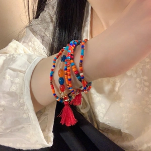 Detailed shot of multi-layer beaded bracelet with red tassels on lace background