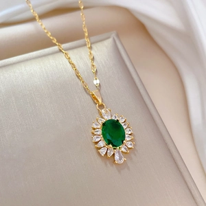 Macro detail of gold necklace with green oval gem and white zircon halo on silk