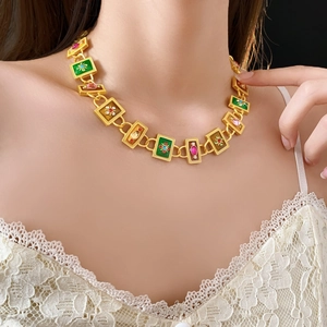 Detail of vintage gold necklace with green and pink gemstones and floral patterns