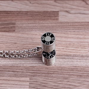 Silver dumbbell pendant necklace with GO FIT engraving on a rustic wood surface
