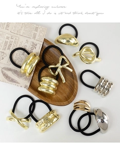 Detailed view of elastic hair ties featuring vintage gold bow and oval metal charms