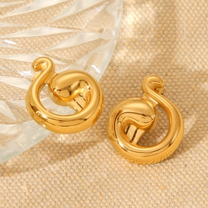 Golden irregular swirl earrings in polished stainless steel on a beige textured fabric