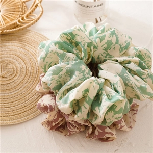 Close-up of oversized floral chiffon scrunchies set in green and red floral patterns