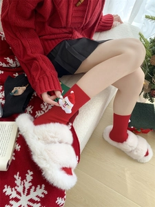 Detail of red Christmas socks with 3D Santa Claus patch and white faux fur slippers