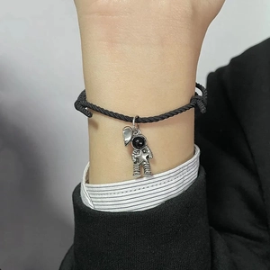 Detail of woven astronaut couple bracelet with silver magnetic charms on wrist