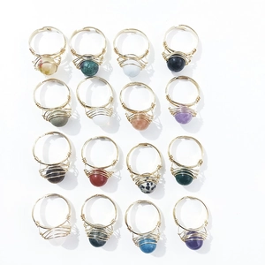 Set of 16 handmade wire wrapped crystal rings with natural stone beads on white background