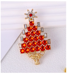 Detailed close-up of golden Christmas tree brooch with red beads and sparkling crystals