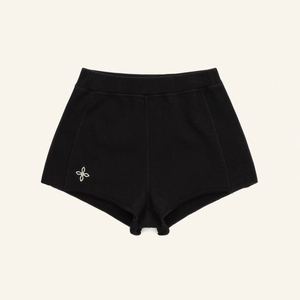 Détail du short de sport en maille noire avec logo fleur blanche brodé sur l'ourlet