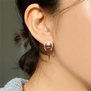 Close-up of minimalist horseshoe pearl earring on model ear in polished sterling silver