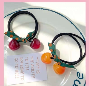 Macro shot of cute cherry hair ties with polka dot bows in a decorative ceramic plate