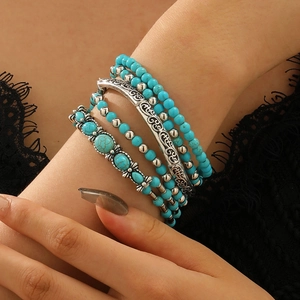 Detail view of Bohemian stackable turquoise bead bracelets and carved silver metal bangles