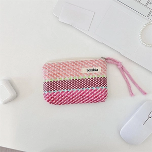 Detailed close-up of woven striped makeup bag with colorful patterns and zip puller