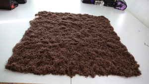 Detailed macro view of artificial moss turf with realistic dark brown fibrous texture