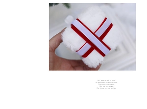 Close-up of white plush gift box ornament with crossed red and purple ribbons