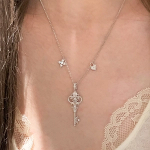 Detailed macro of a stainless steel key pendant necklace with star and heart charms