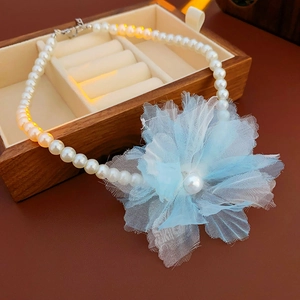 Close-up of mesh flower necklace with pearls in a wooden jewelry box with lighting