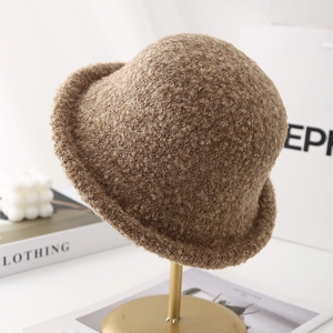 Detailed texture of khaki plush faux shearling bucket hat on a gold display stand