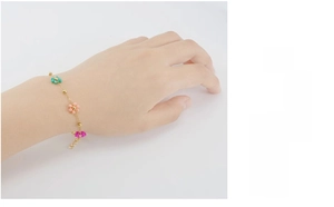 Detail of gold chain bracelet with colorful crystal flowers and adjustable clasp on wrist