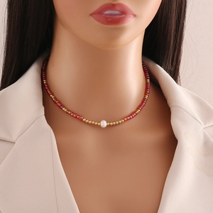Close-up of bohemian red and gold bead necklace featuring a natural white pearl pendant