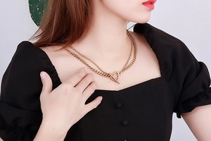 Close-up of double-layer gold chain necklace with heart pendant and OT toggle clasp